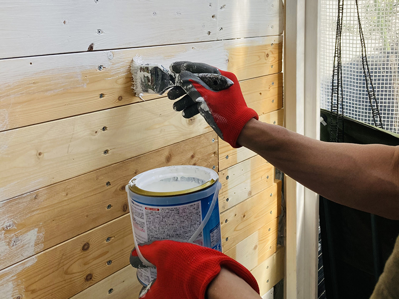 壁を塗装している軍手をした右手